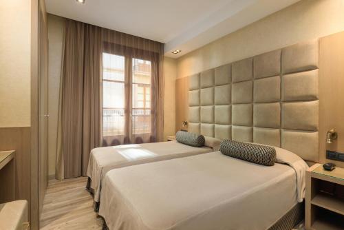 巴塞罗那瑞士酒店的一间卧室设有两张床和窗户。