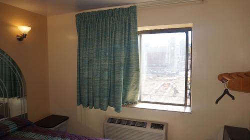 皇后区法拉盛汽车旅馆的卧室设有窗户、一张床和风扇
