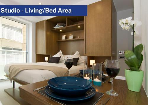 直布罗陀Bentley Holiday Apartments - West One的一间卧室配有一张床和一张桌子及一杯葡萄酒