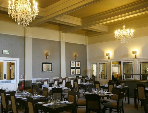 格雷斯瑟罗克Best Western Thurrock Hotel的用餐室配有桌椅和吊灯。