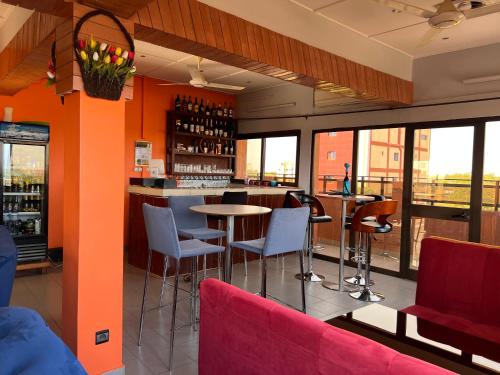 瓦加杜古AG HOTEL Ouaga的餐厅设有酒吧,配有桌椅