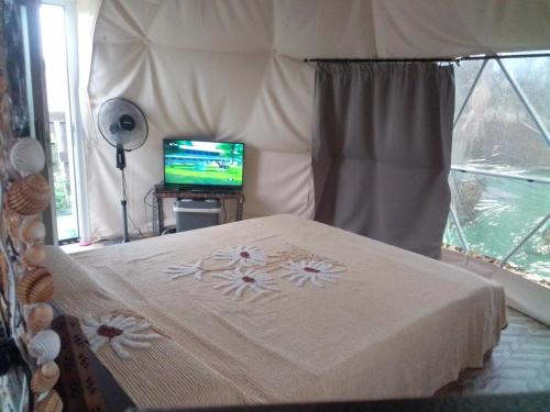 DecimomannuPodere Kiri Dome Experience的一间卧室配有一张床铺,帐篷内配有电视