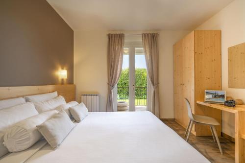 西尔米奥奈比安卡住宅酒店的卧室配有一张白色大床和一张书桌