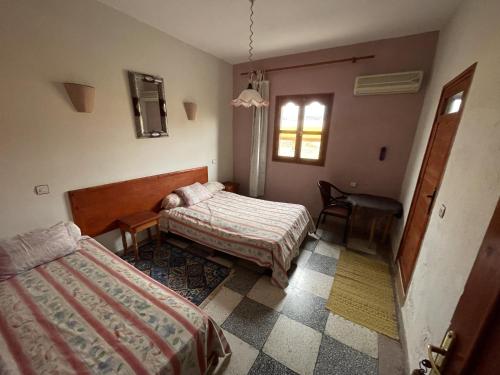 艾济拉勒Hotel Tanout的一间卧室配有两张床、一张桌子和一把椅子