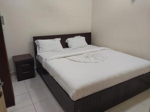 朱巴Tulba Hotel and Residences的一张铺有白色床单的床和木制床头板