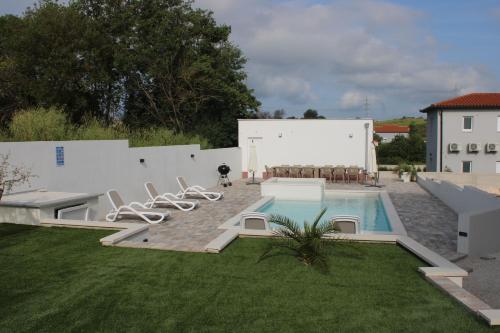 普拉Holiday House emjalemi的后院,在大楼旁边设有游泳池及椅子