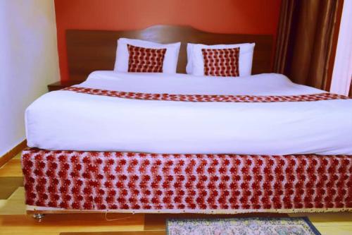 基加利Hôtel Saint Jean Leopold的一间卧室配有一张大床和红色床头板