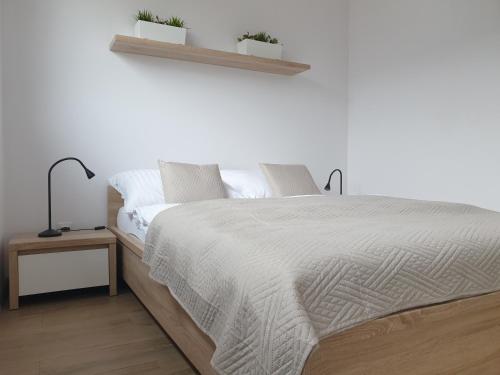 克拉科夫Near the airport- Apartments的白色卧室设有一张大床和两棵植物