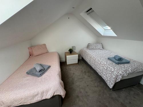埃奇韦尔Charming 4 Bed House, 20 Minutes to Central London的阁楼卧室设有两张单人床和窗户。