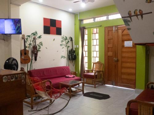 伊基托斯Moicca Youth Hostel的客厅配有红色的沙发和墙上的吉他