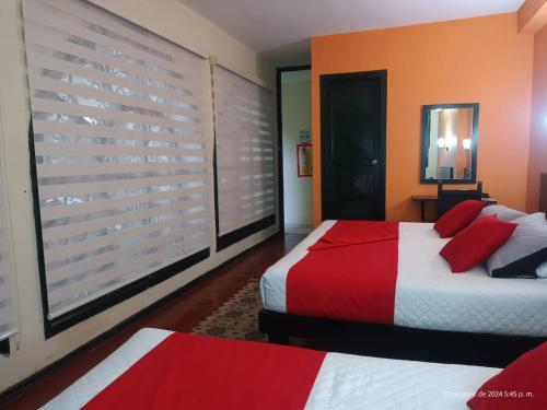 波帕扬Hotel La Herreria Colonial的一间卧室配有两张带红色枕头的床