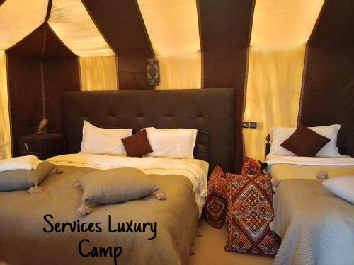 梅尔祖卡Services Luxury Camp的一间卧室设有两张床,里面饲养着动物。
