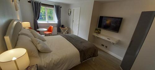 水上伯顿Cotswold Merrymouth Inn的一间卧室配有一张大床和电视