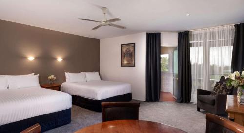 罗托鲁瓦Arawa Park Hotel, Independent Collection by EVT的酒店客房设有两张床和一张桌子。