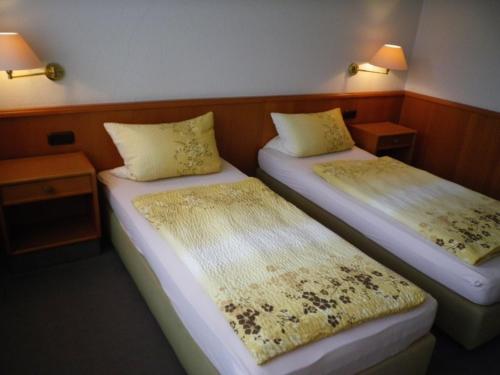 奥尔登堡Stadthotel Oldenburg的配有两盏灯的小房间内的两张床