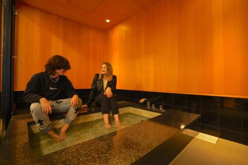 东京COGO Ryogoku的男人和女人坐在浴室的水槽上