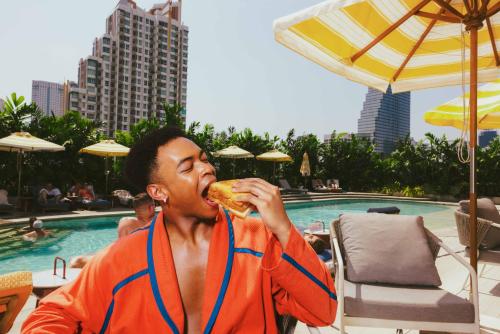 曼谷曼谷仕丹德大京都大厦酒店的一个人在游泳池前吃三明治