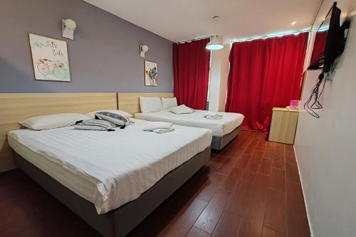 怡保Hotel 18的配有红色窗帘的酒店客房的两张床