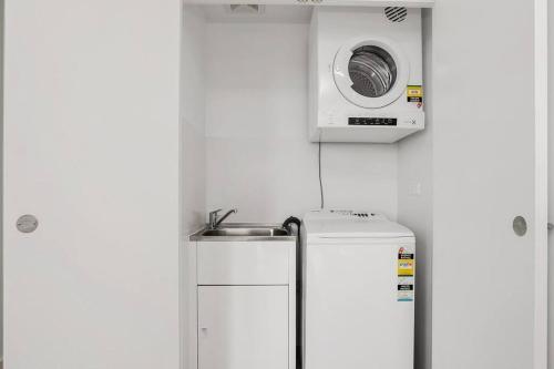 悉尼Stunning Apartment ATC61101的小厨房配有冰箱上方的微波炉