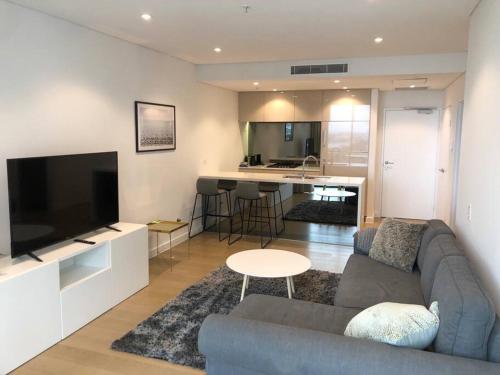 悉尼Stunning Apartment ATC61101的带沙发和电视的客厅以及厨房。
