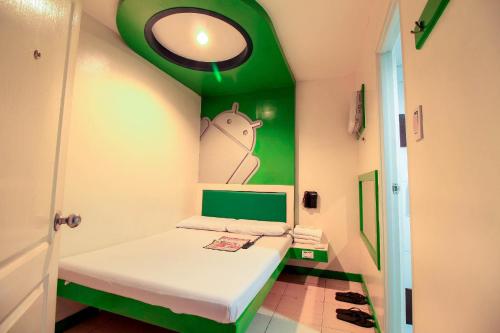 卡兰巴Astrotel Calamba的小房间设有一张带绿色墙壁的床