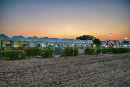 斋沙默尔Royal Adventure Camp & Resort的日落时在海滩上一排帐篷