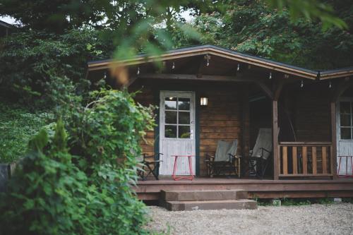 北斗市Premium villa glamping log cabin with stars and bonfire的小木屋前设有门廊和椅子