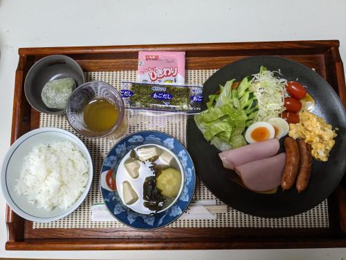 来民民泊サライ七城的包括香肠米饭和蔬菜的食品托盘