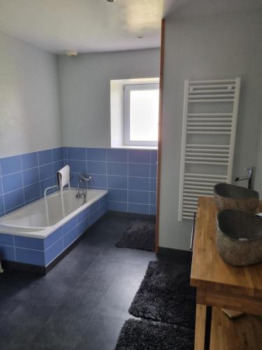 Belleville-sur-VieAu calme et détente的蓝色的浴室设有浴缸和水槽