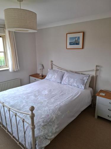 布莱克尼Blakeney Norfolk Bramble Lodge ***Self Catering***的一间卧室配有一张带白色床罩的床