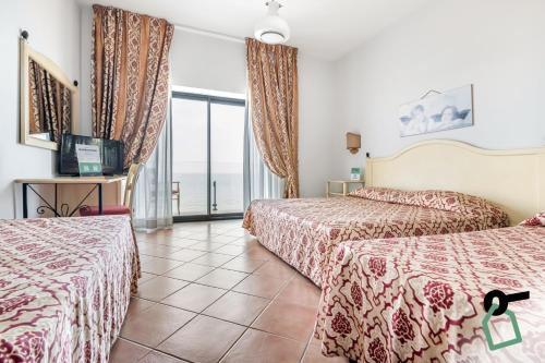 切法卢HOTIDAY Hotel Cefalù的酒店客房设有两张床和一个阳台。