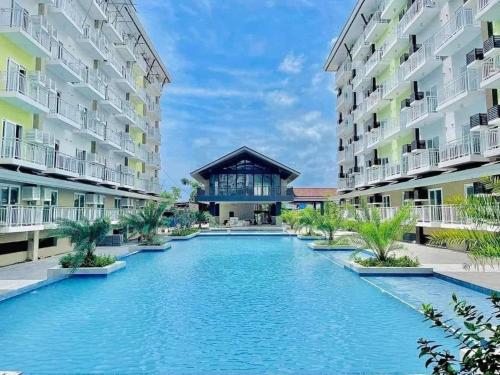 麦克坦119 Amani Grand Mactan Resort的两个公寓大楼中间的一个游泳池