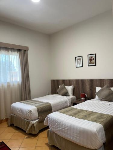 泰布克اجنحة مجمع القوافل الفندقيه的酒店客房设有两张床和窗户。