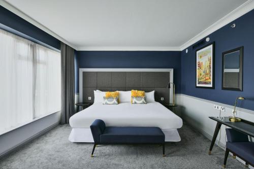 希灵登喜来登希斯罗酒店的卧室配有白色大床和蓝色的墙壁