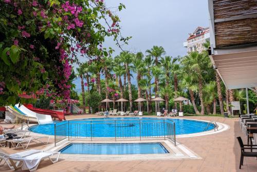 安塔利亚UK Hotel Kiriş的一个带桌椅的度假村游泳池