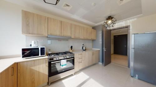 迪拜Unlock Metropolis Business Bay的厨房配有木制橱柜、炉灶和微波炉。