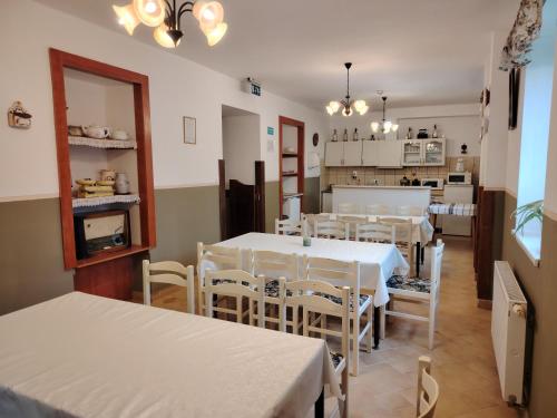 比克克森特凯赖斯特Ódon Panzió的一间配备有白色桌椅的用餐室和一间厨房