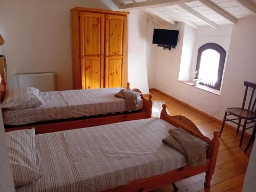 Su Mulinu的一间卧室设有两张床,墙上配有电视。