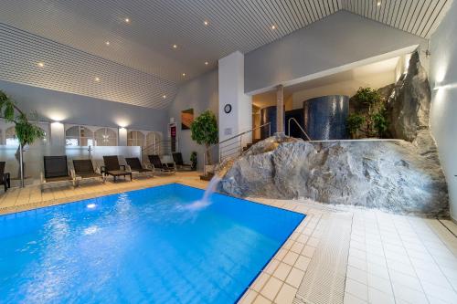 克莱沃Koener Hotel & Spa的一座大型游泳池,位于酒店客房内,设有瀑布