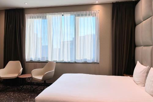 阿姆斯特丹乐维尔酒店的一间卧室配有一张床、两把椅子和一个窗户