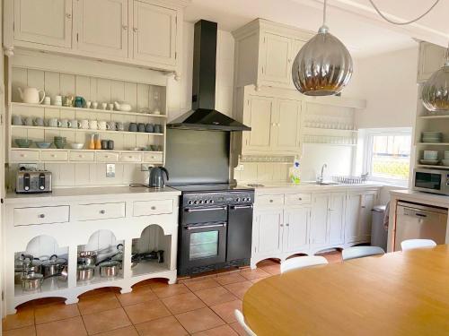 卡纳芬Close to Snowdon with Mountain views of Snowdonia的厨房配有白色橱柜、炉灶和桌子。