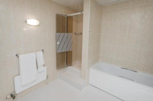 胡克贝辛斯托克Spa酒店的白色的浴室设有浴缸和淋浴。