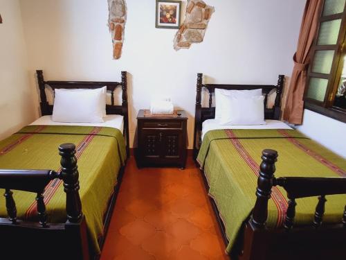 危地马拉安地瓜La Quinta Santa Lucia的一间卧室配有两张床和一张桌子及床头柜
