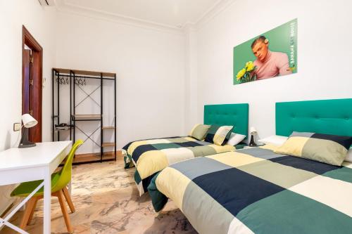 塞维利亚Banana Gay House - Only Men的客房设有两张床、一张桌子和一张书桌。