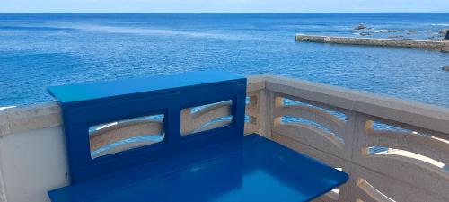 AlojeraVv Puesta de Sol的蓝色长椅,坐在俯瞰大海的墙上