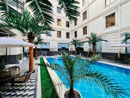 撒马尔罕Medina Hotel Samarkand的一座酒店游泳池,在一座建筑前有棕榈树