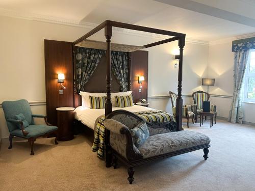 Oakmere纳斯梅尔礼堂酒店的一间卧室配有四柱床和椅子