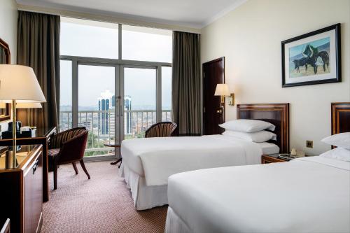 坎帕拉Sheraton Kampala Hotel的酒店客房设有两张床和窗户。