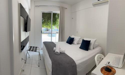 阿奎拉兹PALM BEACH Porto das Dunas, apartamento todo climatizado TÉRREO a 350 metros Beach Park的白色卧室配有一张大床和一张书桌