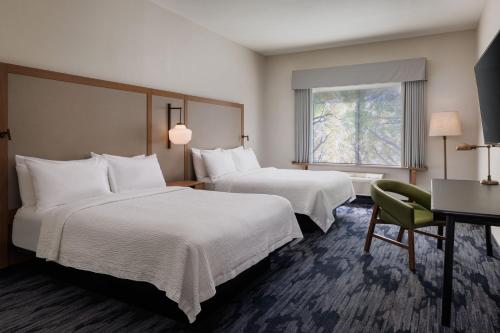 基洛纳Fairfield Inn & Suites by Marriott Kelowna的酒店客房设有两张床、一张书桌和一个窗户。